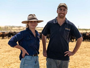 Two producers standing, facing the camera, with cattle in the background